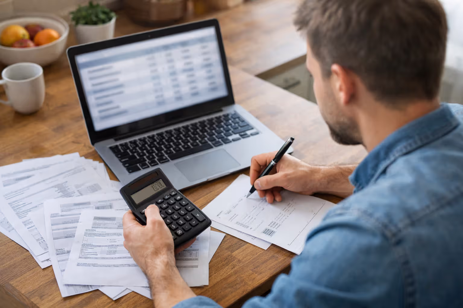 Homeowner researching insurance rates on a laptop with a notebook and smartphone on a desk