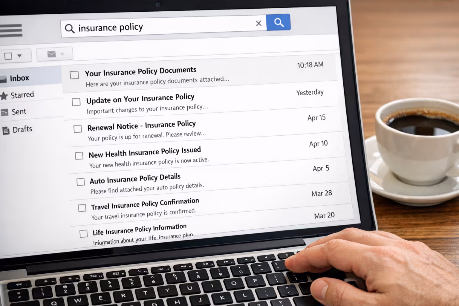 Laptop screen showing email inbox search for insurance policy documents with search bar and email list visible